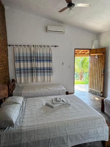 a bedroom with two beds and a ceiling fan at Pousada Ana Maria in Delfinópolis