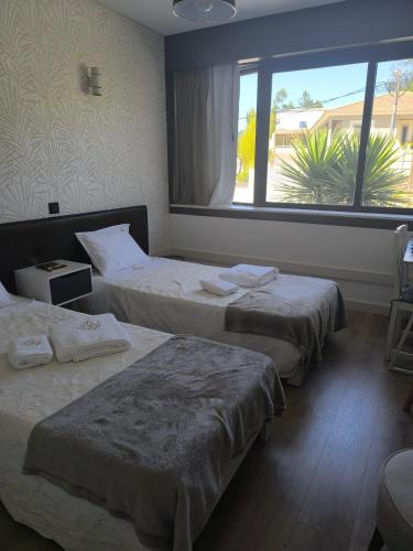 three beds in a room with a large window at Aromas do Vouga in São Pedro do Sul