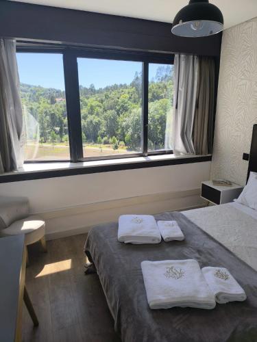 a bedroom with two towels on a bed with a window at Aromas do Vouga in São Pedro do Sul