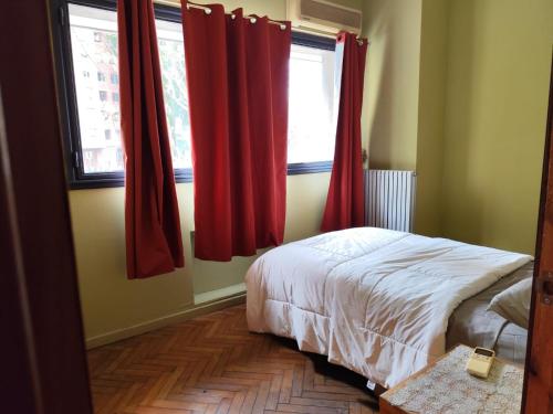 a bedroom with red curtains and a bed and a window at Libertador 4 MVD in Montevideo
