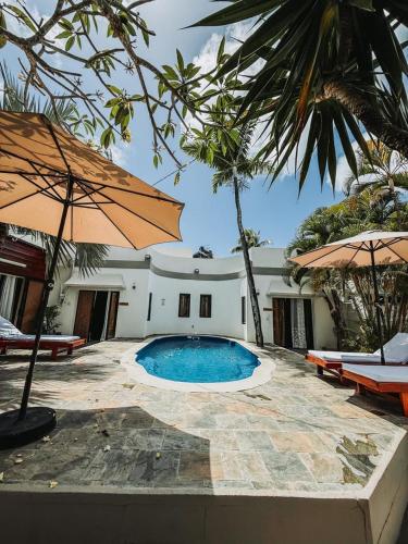 a swimming pool with two umbrellas next to a building at The Coastal Charm in Grand-Baie