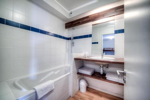 a bathroom with a sink and a tub and a mirror at Zenitude Hôtel-Résidences l'Acacia Lourdes in Lourdes