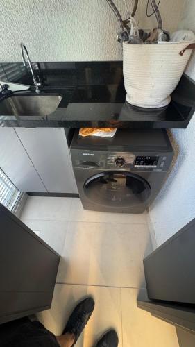 Apt luxo vista mar 160m com jacuzzi e 2 garagens في ايتابيما: شخص واقف في مطبخ مع موقد