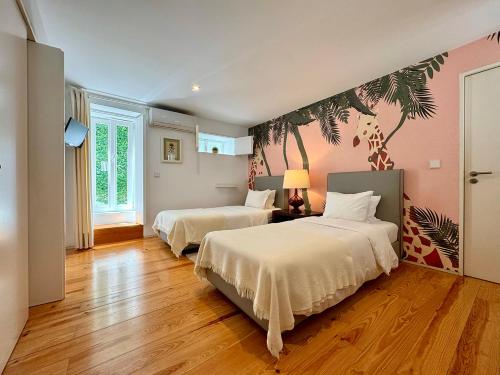 two beds in a bedroom with pink walls and wooden floors at Casa das Laranjas in Porto