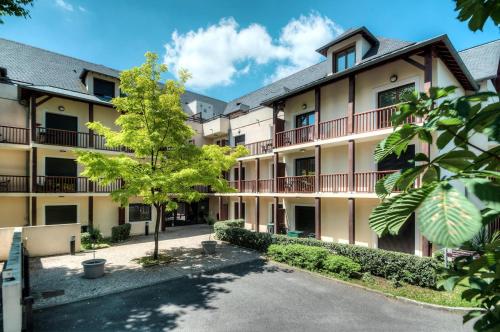 an exterior view of a building with a courtyard at Comfort Aparthotel Lourdes L'Acacia in Lourdes