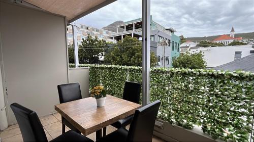 ケープタウンにあるSweetStay - Kloof Streetのバルコニー(木製のテーブルと椅子、窓付)