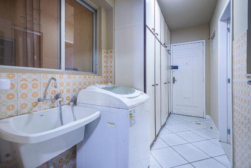 a bathroom with a sink and a tub and a mirror at IPTZ170- Frente mar c/ vista incrível do 17º andar in Balneário Camboriú