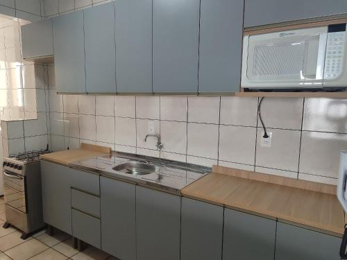 a kitchen with a sink and a microwave at Aptos completos em Meia Praia a 150m do Mar - EOOs in Meia Praia