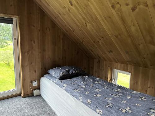 a bed in a room with a wooden ceiling at Architectural gem with fjord view in Holmedal