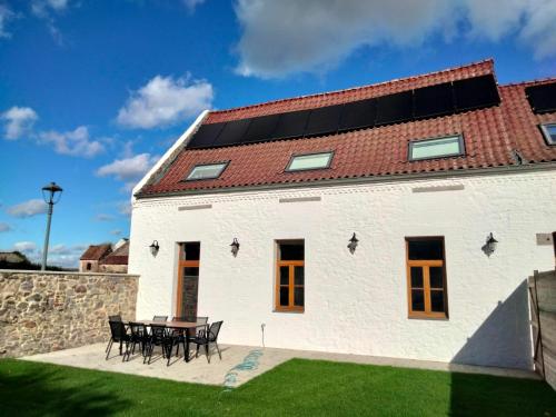 a white building with a table and a red roof at Les Campanes - Gite 8 personnes avec piscine intérieure et sauna 