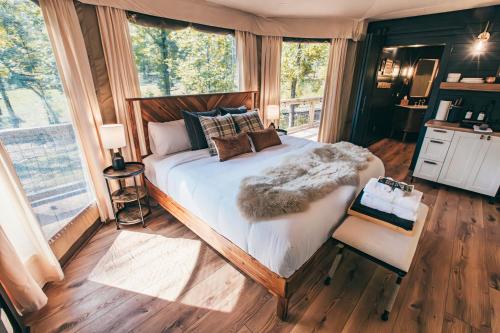 a bedroom with a large bed and a window at Luxuring Glamping Tent - The Dog Wood - Near Tryon International Equestrian Center - Wheat Creek Outpost in Mill Spring