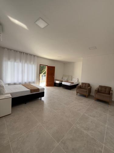 une chambre avec deux lits et un canapé et des chaises dans l'établissement Mansão Essência Pipa, à Pipa