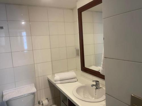 Un baño con lavabo, espejo e inodoro. en Foresta Urban Suites, en Santiago