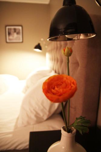 a vase with a flower on a table next to a bed at Haukeli Hotel in Haukeligrend