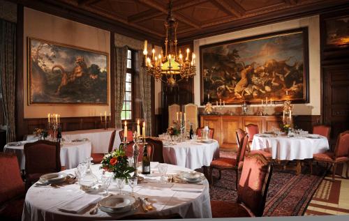 une salle à manger avec deux tables et des nappes blanches dans l'établissement Chateau de Canisy, à Canisy