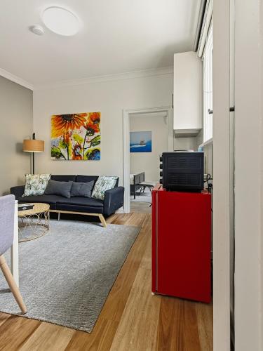 a living room with a couch and a red refrigerator at Charming 1 bedroom, park adjacent. city 5 minutes in Sydney