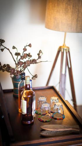 a table with a bottle of whiskey and glasses on it at Ololo Safari Lodge & Farm in Nairobi