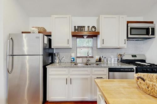 a kitchen with white cabinets and a stainless steel refrigerator at Hyde Park Carriage House in Austin