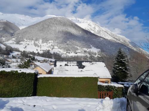 a house covered in snow with a mountain in the background at Cauterets in Cauterets