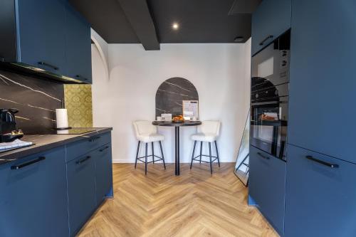 a kitchen with blue cabinets and a table with stools at Prisma - Univers du jeux in Chagny