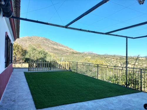 a balcony with a lawn with a mountain in the background at El Almendro de Fuentes Nuevas in Castril