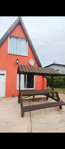 een houten picknicktafel voor een rood huis bij Colibríes Dorados in Mar del Plata