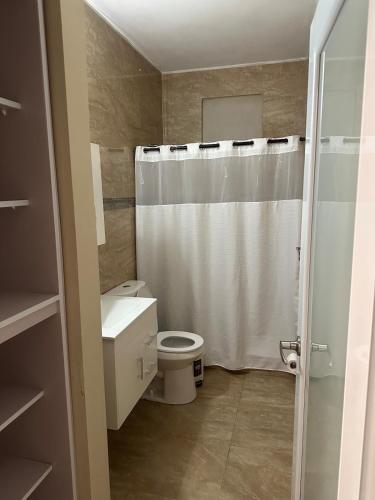 ein Badezimmer mit weißem Duschvorhang und Toilette in der Unterkunft Casa Bayaverde in Bayamon