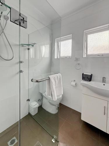 a white bathroom with a toilet and a sink at Cute 1 bedroom with sunny courtyard garden in Sydney