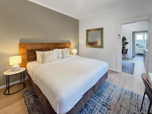 a bedroom with a large white bed and a mirror at Cute 1 bedroom with sunny courtyard garden in Sydney