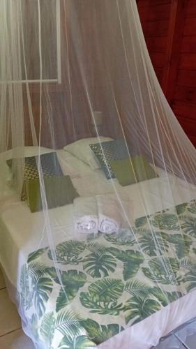 a bed with a mosquito net on top of it at Bungalow nature zen in Le Gosier