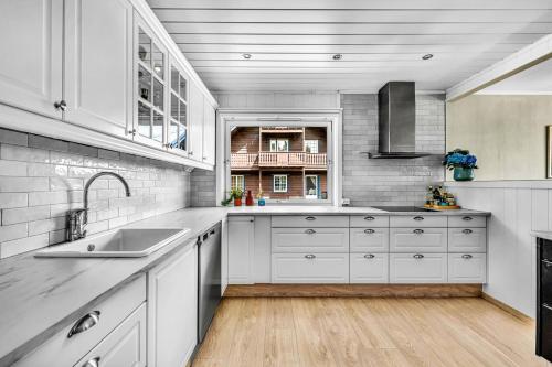 Una cocina con gabinetes blancos y un fregadero. en House in Rotnes, Nittedal, en Nittedal