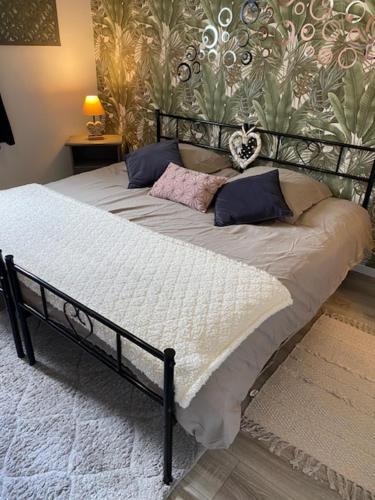 a large bed with pillows and a wall at Charmant Logis a la campagne in Ardentes