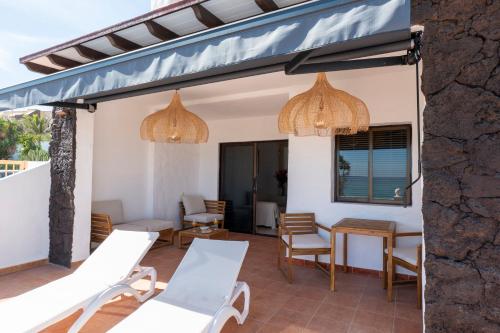 a patio with white chairs and a blue awning at Sand & Beach in Pájara