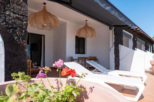 an outdoor patio with white chairs and flowers at Sand & Beach in Pájara