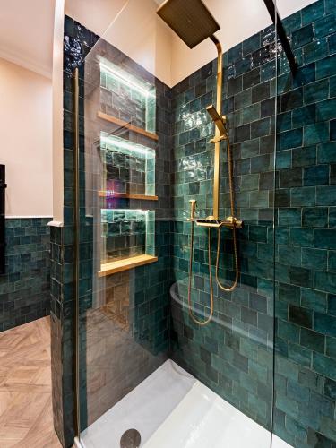 a bathroom with a shower with green tiles at Strands Of Time Hotel Bruges in Bruges
