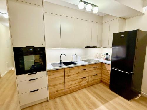 a kitchen with white cabinets and a black refrigerator at Apartament Kaszmir in Kętrzyn