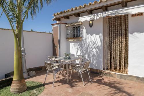 a table and chairs on a patio with a palm tree at Casas con piscina compartidas Garaje y Wi-Fi in Roche
