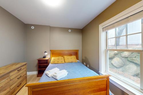 a bedroom with a bed with blue sheets and a window at Summer Cape Escape in Dennis Port