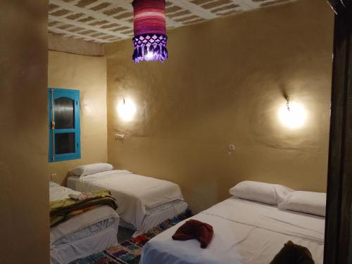 a room with three beds and a chandelier at Gîte Palma Eagle Ziz Canyon in Er Rachidia