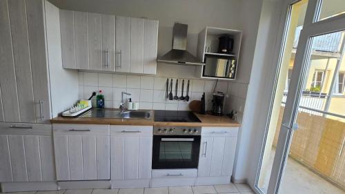Eine Küche mit weißen Schränken, Spüle und Herd in der Unterkunft 3-Raum-Wohnung beim Luther in Chemnitz