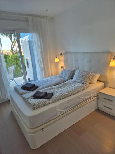 ein großes weißes Bett mit zwei schwarzen Handtüchern darauf in der Unterkunft Hilly's Place in Roldán