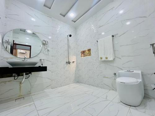 a white bathroom with a toilet and a sink at Best Eastern Hotel Multan in Multan