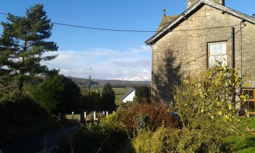 an old stone house with mountains in the background at Plumtree House in Brigsteer
