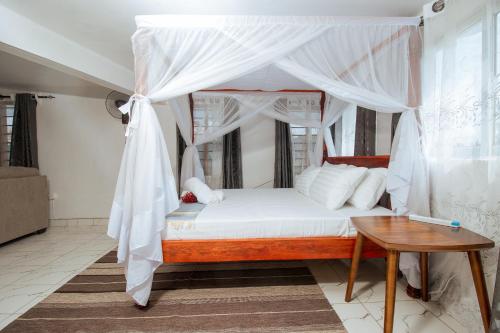 Stylish Studio, Pool and Walk to Beach في واتامو: غرفة نوم مع سرير المظلة وطاولة