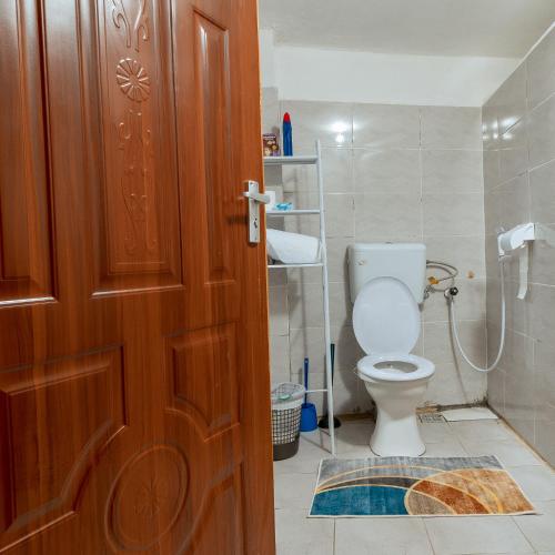 a bathroom with a toilet and a wooden door at Stylish Studio, Pool and Walk to Beach in Watamu