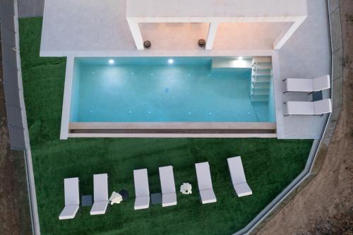 an overhead view of a swimming pool with white chairs at Villa Marco in Zakynthos Town