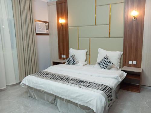 Un dormitorio con una gran cama blanca con almohadas. en فخامة مسرة لشقق المخدومة, en Taif