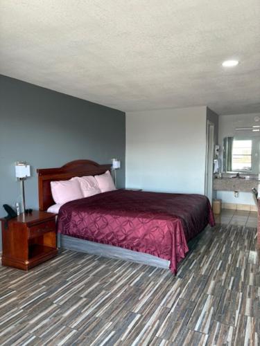 a bedroom with a bed with a red bedspread at Plaza Inn in Big Spring