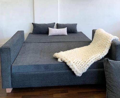 a blue couch with a pillow and a blanket at Departamento moderno en CABA in Buenos Aires