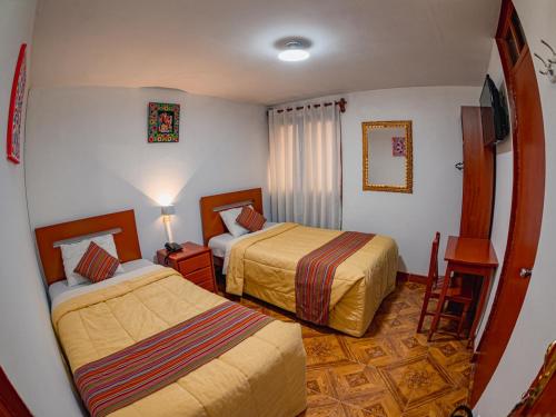 a hotel room with two beds and a table at Hotel San Francisco de Paula in Ayacucho